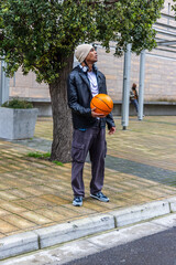 Fototapeta premium Diverse males standing, holding orange basketball, wearing beanie and headphones at plaza