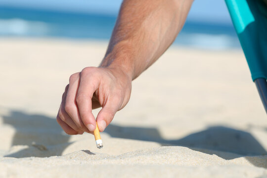 man finishing a cigarette on the beach