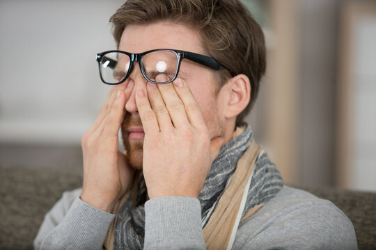 man wearing eyeglasses rubbing his eyes