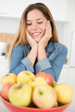 happy woman looking at fresh apples in kitchen