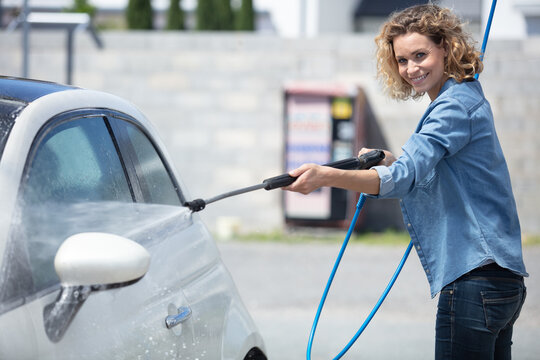 young woman washing her car with sponge