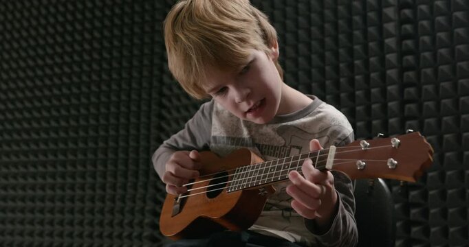 Boy Play Music on Ukulele Instrument in Home Studio. 4K 10-bit
