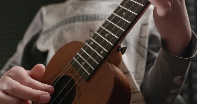 Boy Play Music on Ukulele Instrument in Home Studio. 4K 10-bit