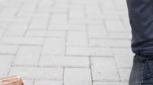 Unthinking individual tosses nearly empty plastic coffee cup onto paved ground, littering environment.