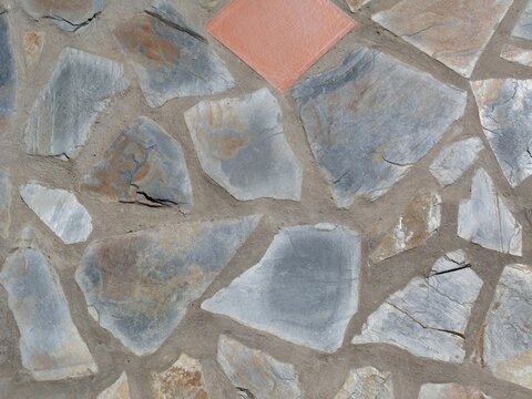 Stone wall with irregular flagstones and orange tile