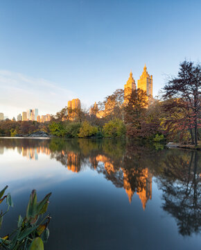Autumn landscape reflecting the San Remo buildings on the Lake in Central Park, Manhattan, New York City, providing a peaceful travel and tourism destination amidst vibrant fall foliage.