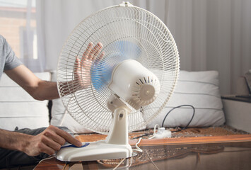 Fototapeta premium Caucasian man with a electric fan at home.