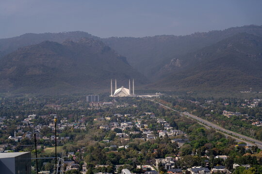 Aerial view of the Faisal Mosque at the foot of the Margalla Hills with the urban landscape and lush greenery of Islamabad, Islamabad Capital Territory, Pakistan.
