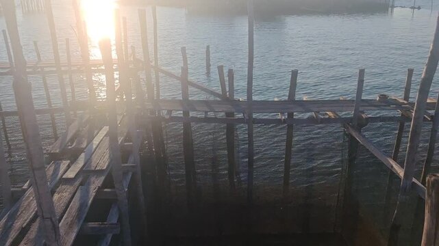 a traditional wooden aquaculture fish cage and boardwalk structure built over the ocean