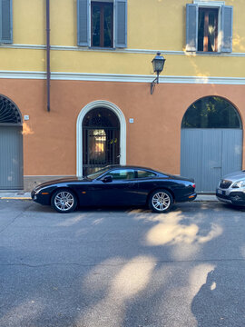 Jaguar XK8 X100 coupe parked on an old European street by an historic building, expressing luxury and classic design