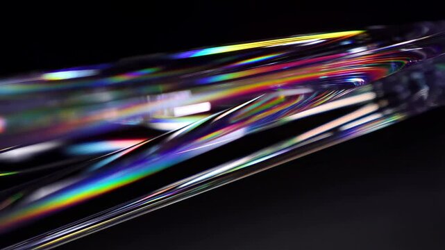 Tracking slow motion shot of iridescent liquid film flowing and rippling on glossy surface in dark studio macro close up