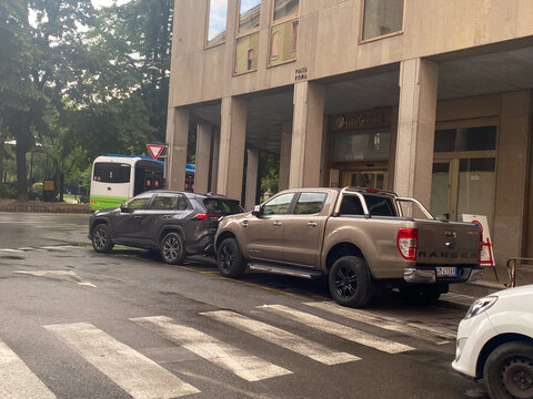Ford Ranger and Toyota RAV4 vehicles parked on an urban street near a UniCredit bank building in Piazza Roma