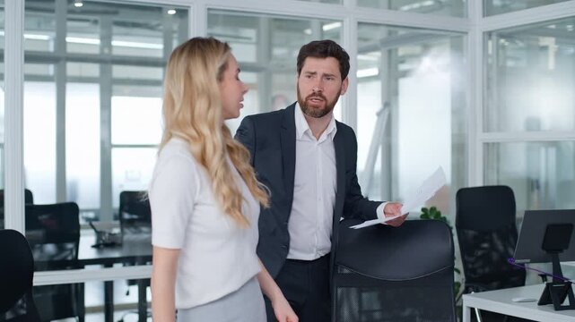 Two business colleagues Caucasian businessman leader furious yelling to businesswoman. Male CEO dissatisfied with documents upset woman listening blaming scolding angry man holding papers work stress
