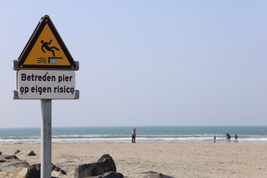 safety sign on the beach: "betreden pier op eigen risico"