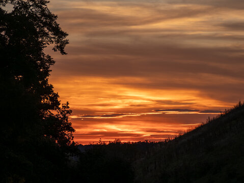 Stimmungsvoller Sonnenuntergang mit leuchtend orangefarbenem Himmel &uuml;ber einer Landschaft. Romantische Abendstimmung, Naturidylle und beeindruckendes Farbenspiel. Echtfoto.