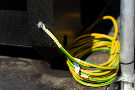 Electrical grounding connection showing a copper lug terminal screwed into a heavy generator frame next to a coiled protective earth wire system
