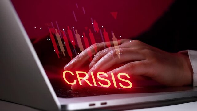 Working on a laptop with financial data and the word crisis displayed on the screen in a dark setting during evening hours