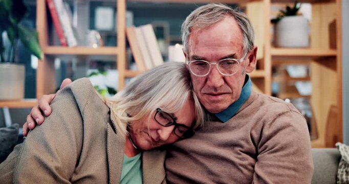 Sad, hug and old couple on home sofa for support, comfort and empathy for person with depression. Embrace, man and woman in retirement together with love, mental health or sorry for loss in house