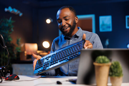 Content creator filming keyboard review in personal studio, pressing different buttons to show typing capabilities. Technology guru showcasing computer periperal to audience on niche online channel
