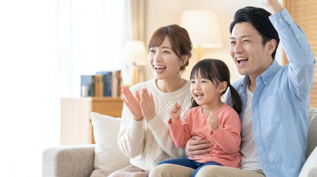 テレビでスポーツ観戦をしてリビングで熱狂しながら応援する笑顔の家族