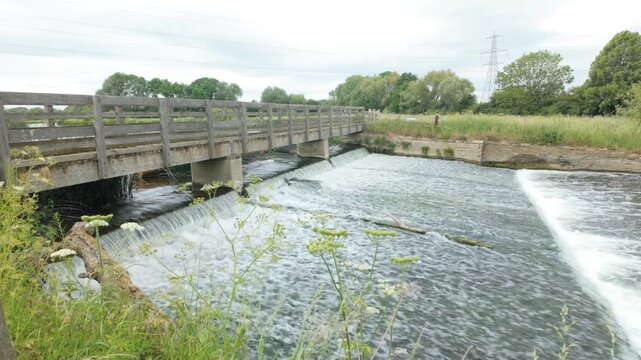 Water Newton, Cambridgeshire, England, UK - June 01 2026: At the Water Newton Weir looking up stream and toward the bridge whilst the water flows fast in summer