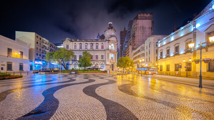 19 April 2026 Beautiful Night Colours of colonial Portuguese buildings in Central old Macau China. Streets filled with tourists viewing the Historical architecture and streets of cobble stones black a © Elias Bitar
