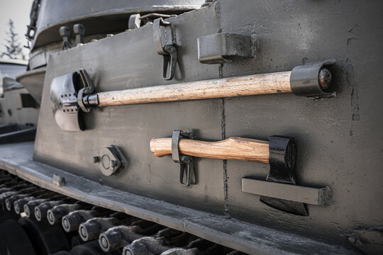 Entrenching tools mounted on side armor of self propelled artillery vehicle, shovel and axe attached to tracked combat machine, close up military equipment details