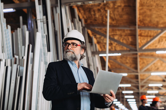 Mature engineer using laptop in window factory