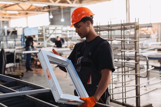 Young worker examining pvc window frame during production