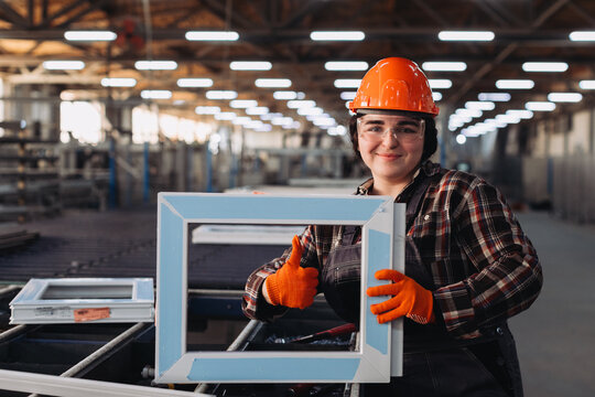 Female worker showing ready window frame in factory