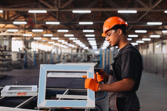 Young worker assembling window frame in factory