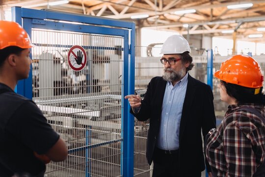 Supervisor explaining factory operations to young industrial workers