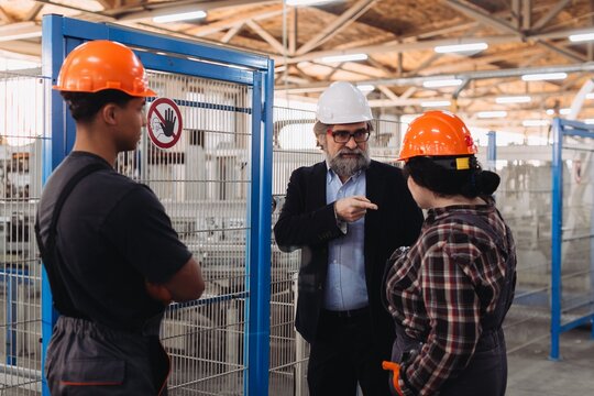 Manager instructing industrial workers during factory discussion