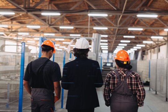 Manager walking with factory workers in manufacturing plant