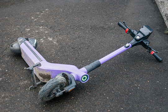 Electric scooter lying on wet asphalt after fall or accident, concept of urban micromobility, road safety and personal electric transportation