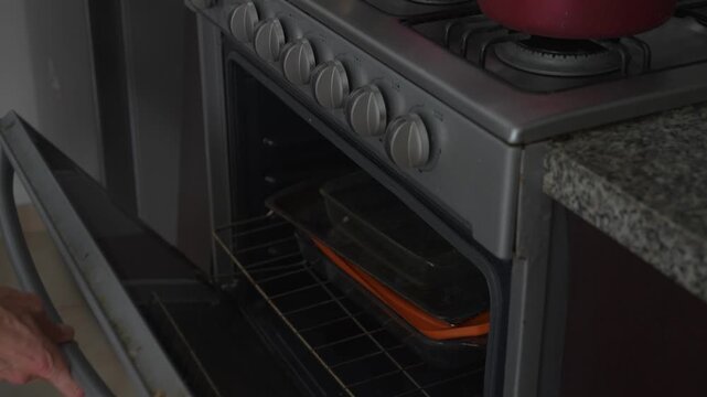 Man opening and closing oven door on kitchen stove in close up with high quality sound. Home cooking, kitchen appliances and everyday household lifestyle concept.