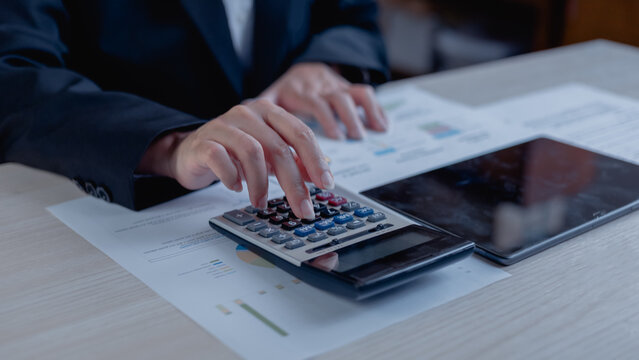 gst vat tax taxation taxes finance financial accounting.Business professional calculating GST and VAT using a calculator with financial reports and charts for accounting, budgeting, tax compliance.