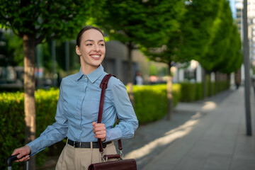 Young woman smiling walking with luggage in city © Jelena
