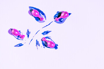 Obraz premium Minimalist composition of vibrant pink cosmetic capsulas nestled in deep blue textured paint strokes on a light lavender background. .