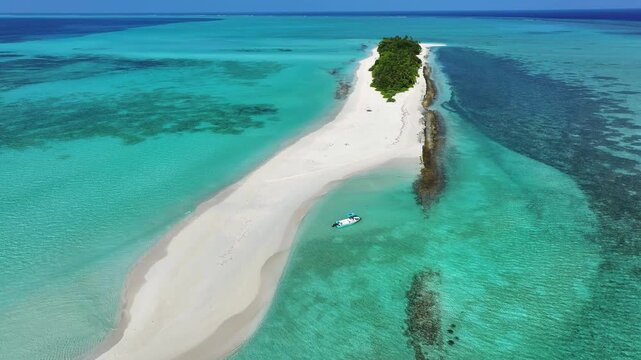 Aerial view of a narrow white sandbar stretching into turquoise ocean waters with a small boat anchored nearby in Fulhadhoo, Baa Atoll, Maldives.
