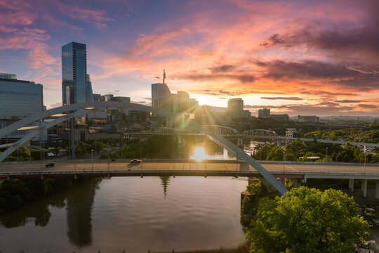 Korean Veterans Memorial Bridge in Nashville city, Tennessee, USA. Highway traffic driving cars in downtown district. American city skyline with brightly illuminated buildings at sunset.