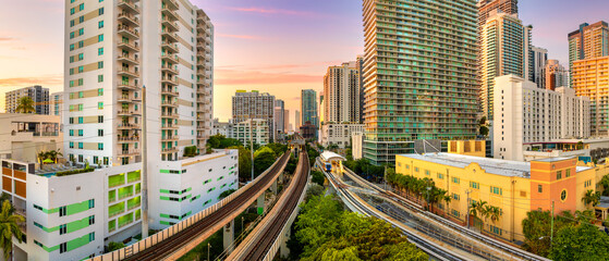 Obraz premium Urban railroad cuts through Miami downtown Brickell district. Public train connecting city between towering American skyscrapers