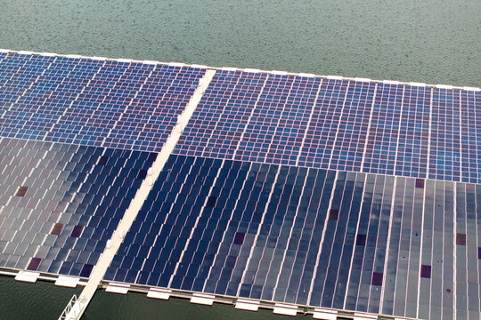 View from above of floating photovoltaic power plant with many rows of solar panels for producing clean electrical energy. Concept of renewable electricity on water surface with no air pollution