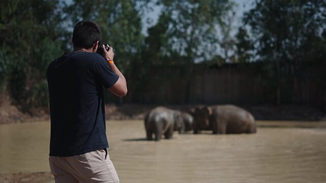 Wildlife photographer taking pictures of elephants bathing
