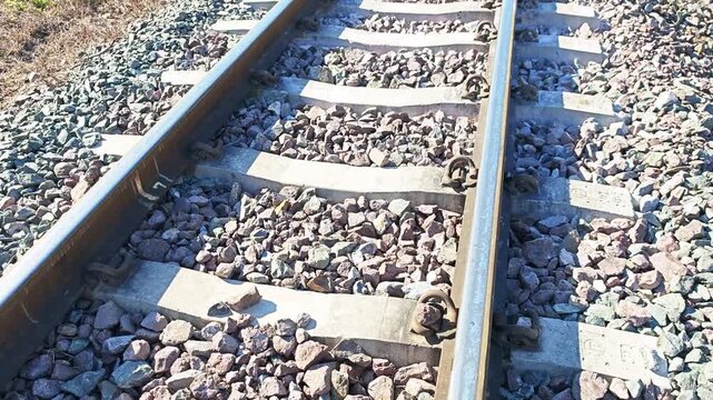 Close-up of railway track steel rails and concrete sleepers with ballast stones.