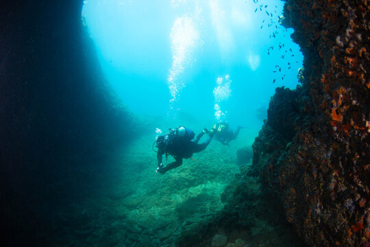 Diving in a rocky underwater area while learning scuba techniques in clear waters
