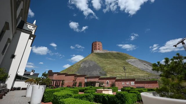 Gediminas Tower stands majestically atop Gediminas Hill under a bright blue sky with white clouds, offering a picturesque view of this historic landmark in Vilnius, Lithuania.