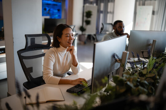 Asian woman actively working at modern open office workplace