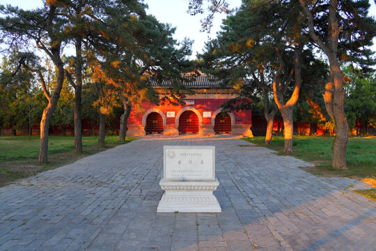 Stele and main entrance gate of Pule Temple complex at sunset with golden light on traditional pine trees, Chengde, Hebei, China