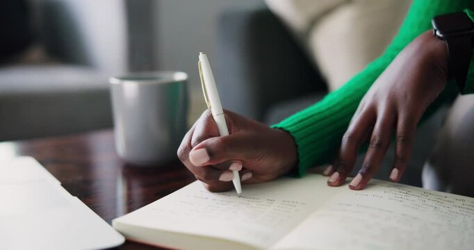 Close-Up of an African American Person's Hands Writing in a Notebook at a Desk